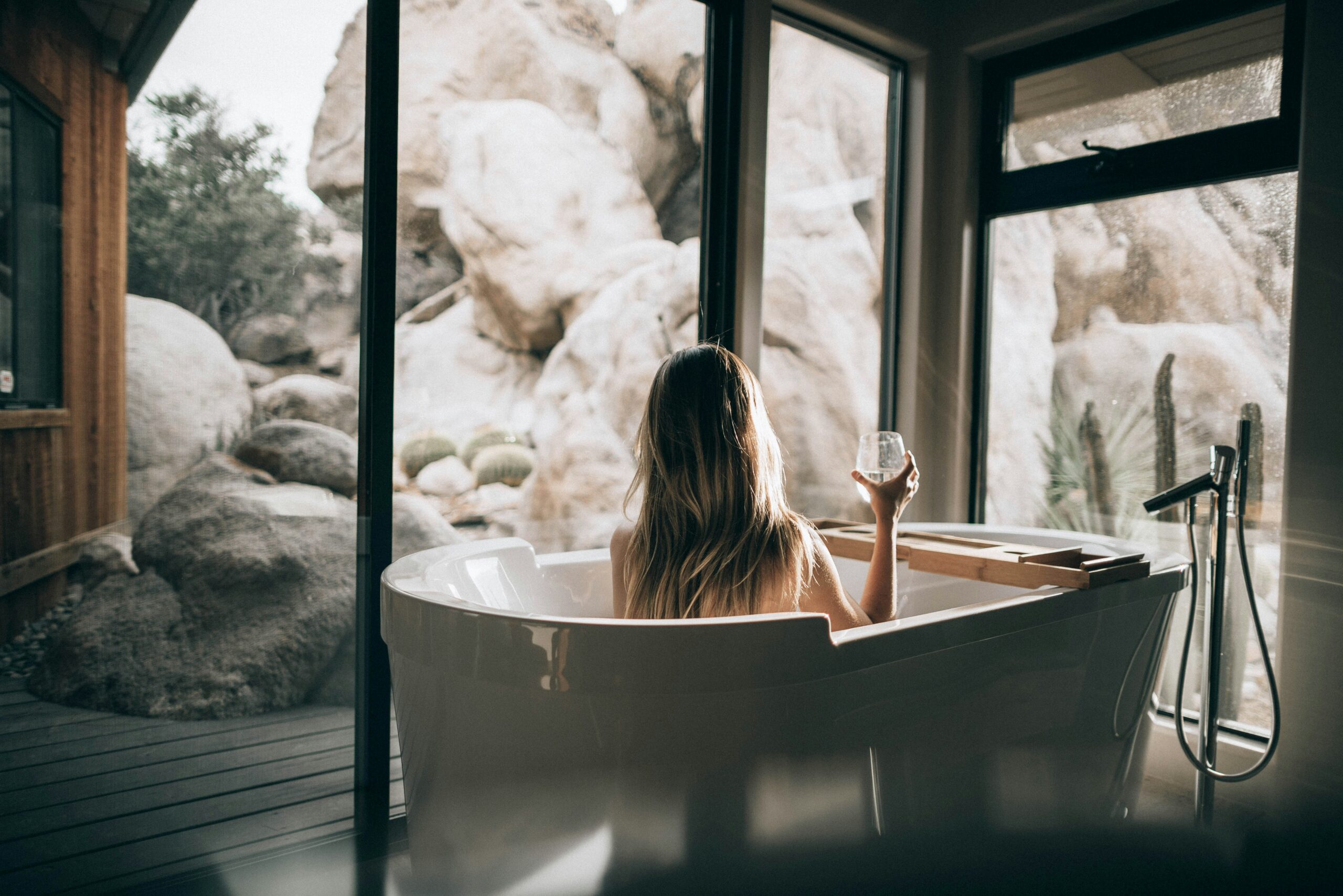 Woman sitting in bathtub with a glass of wine