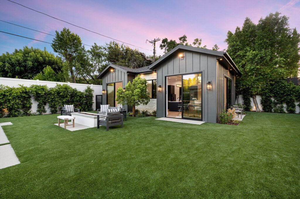 Modern backyard with small house and patio furniture at sunset.