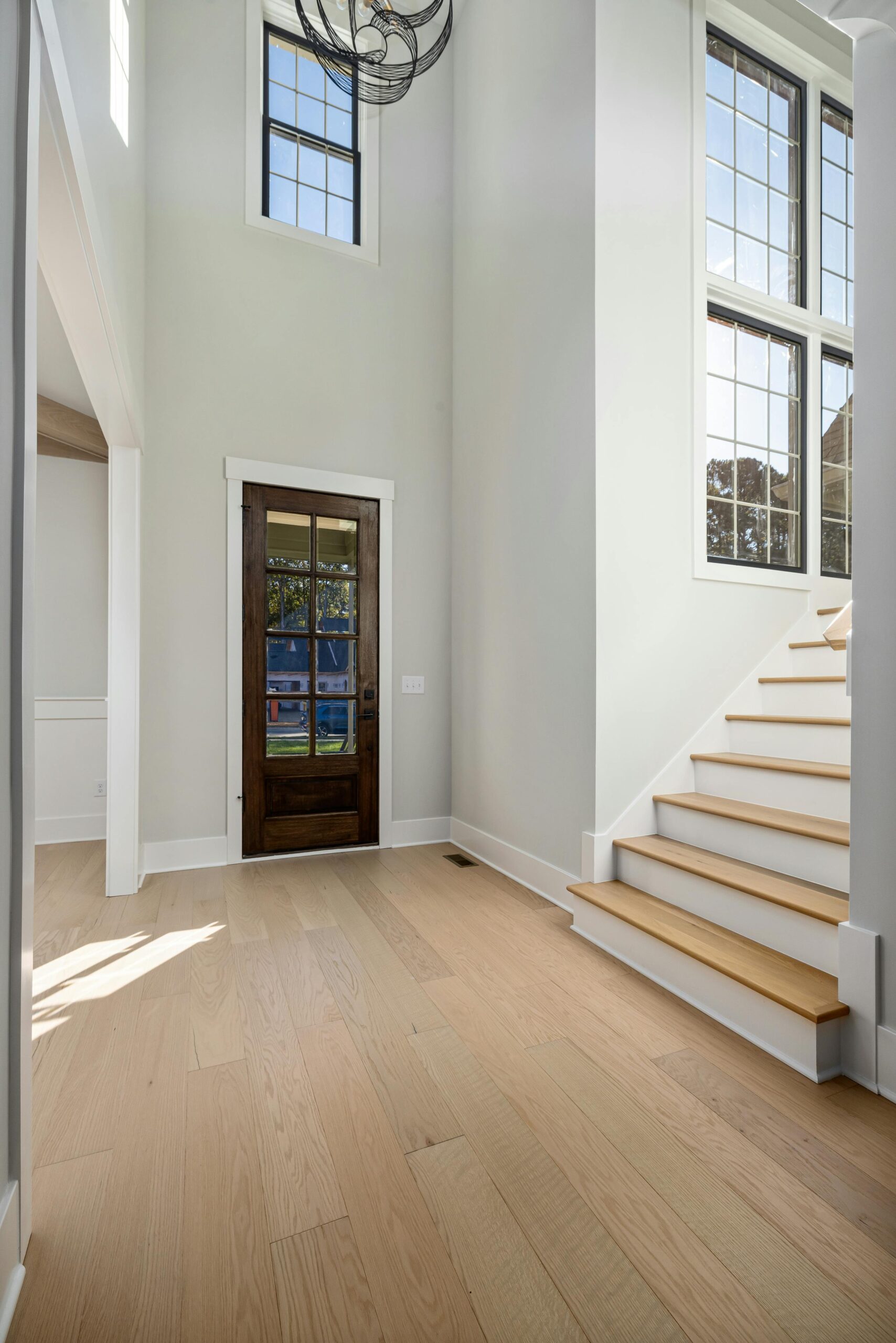 A white hallway with wooden floors & a staircase