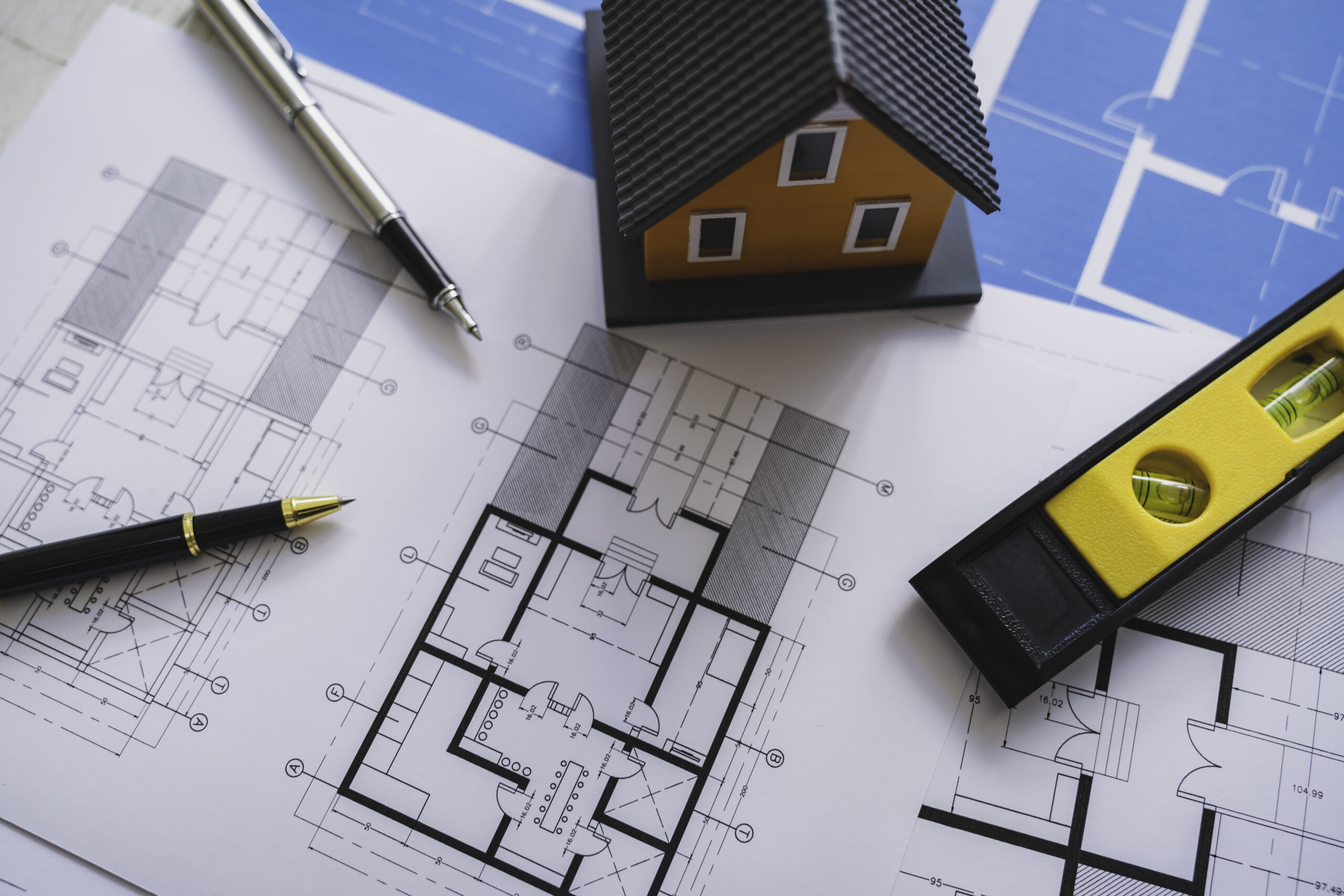 Home blueprints with pens and a leveler.