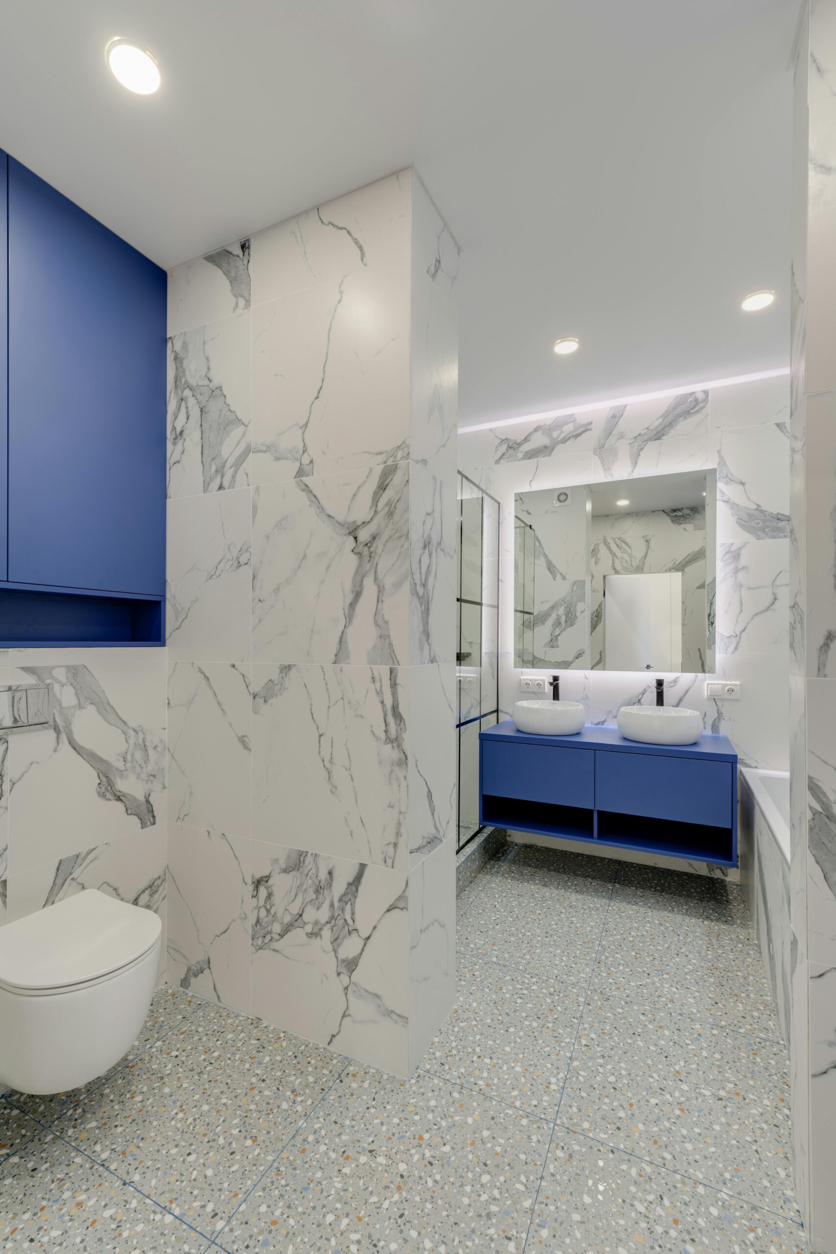 A modern marble bathroom with blue cabinets