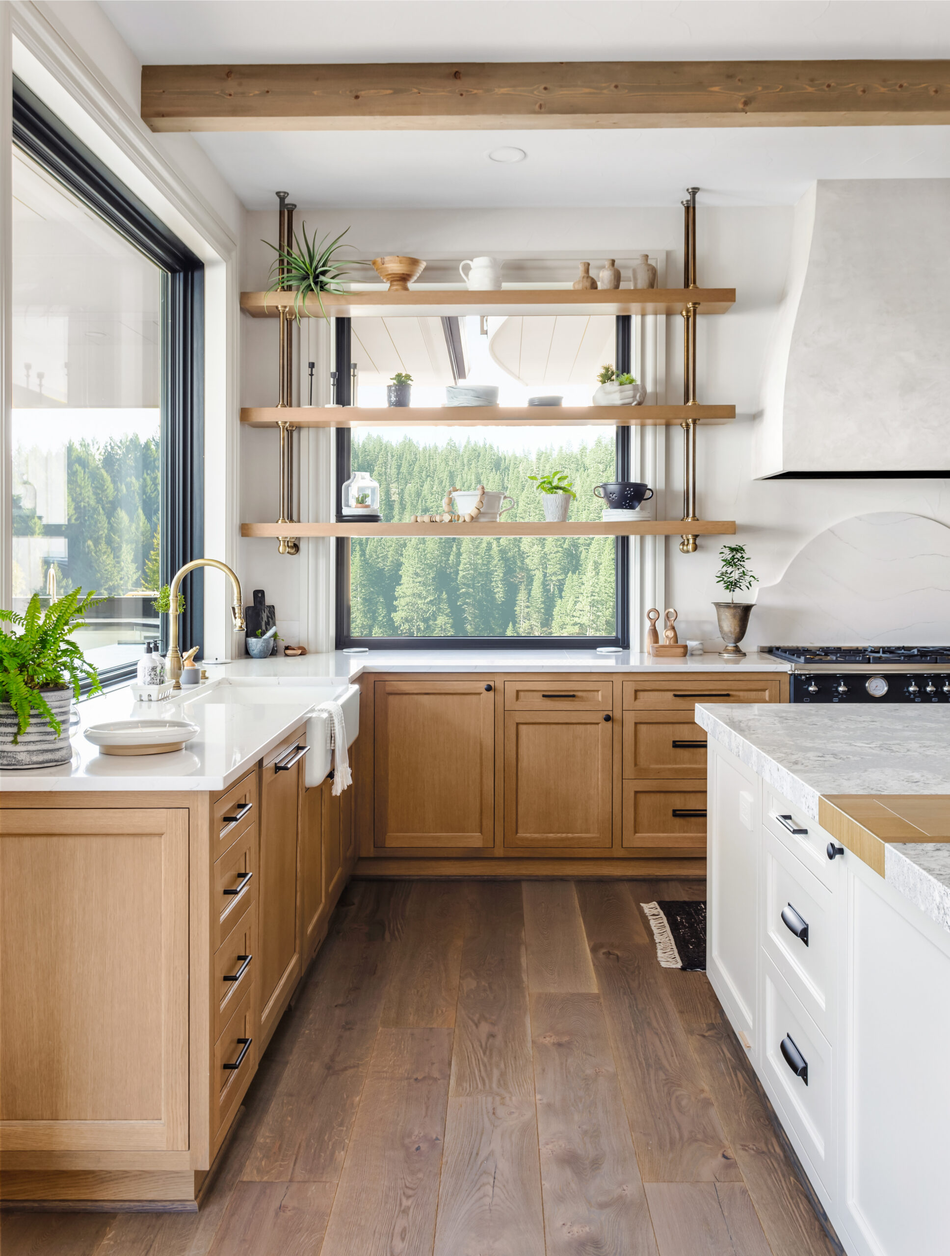 Traditional kitchen with hardwood floors, wood beams, quartz counters & large windows.