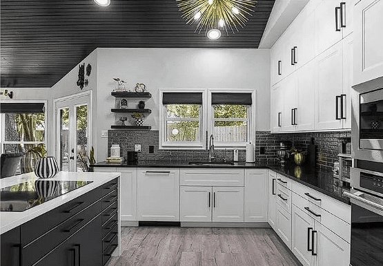 Modern white kitchen remodel with custom cabinetry, black countertops, and backsplash.