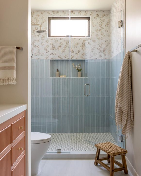 Modern bathroom shower with blue tile and floral accent wall