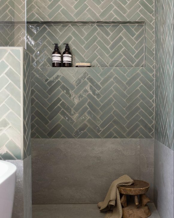 Walk-in shower with green herringbone tile and built-in shower niche